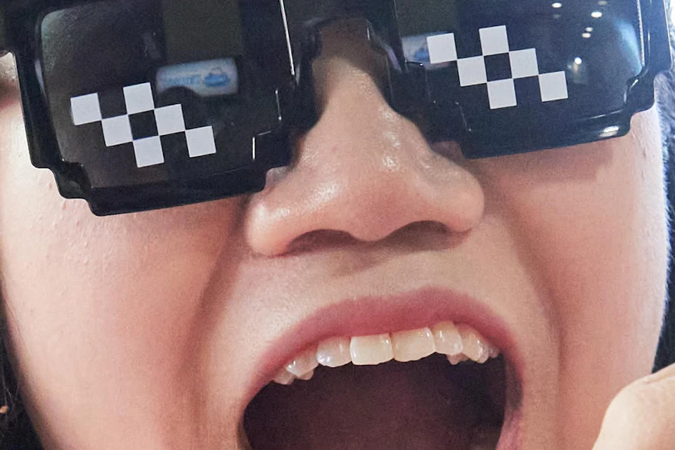 Group of friends sharing food outside; central person wearing pixelated sunglasses excitedly opening mouth near white bowl.