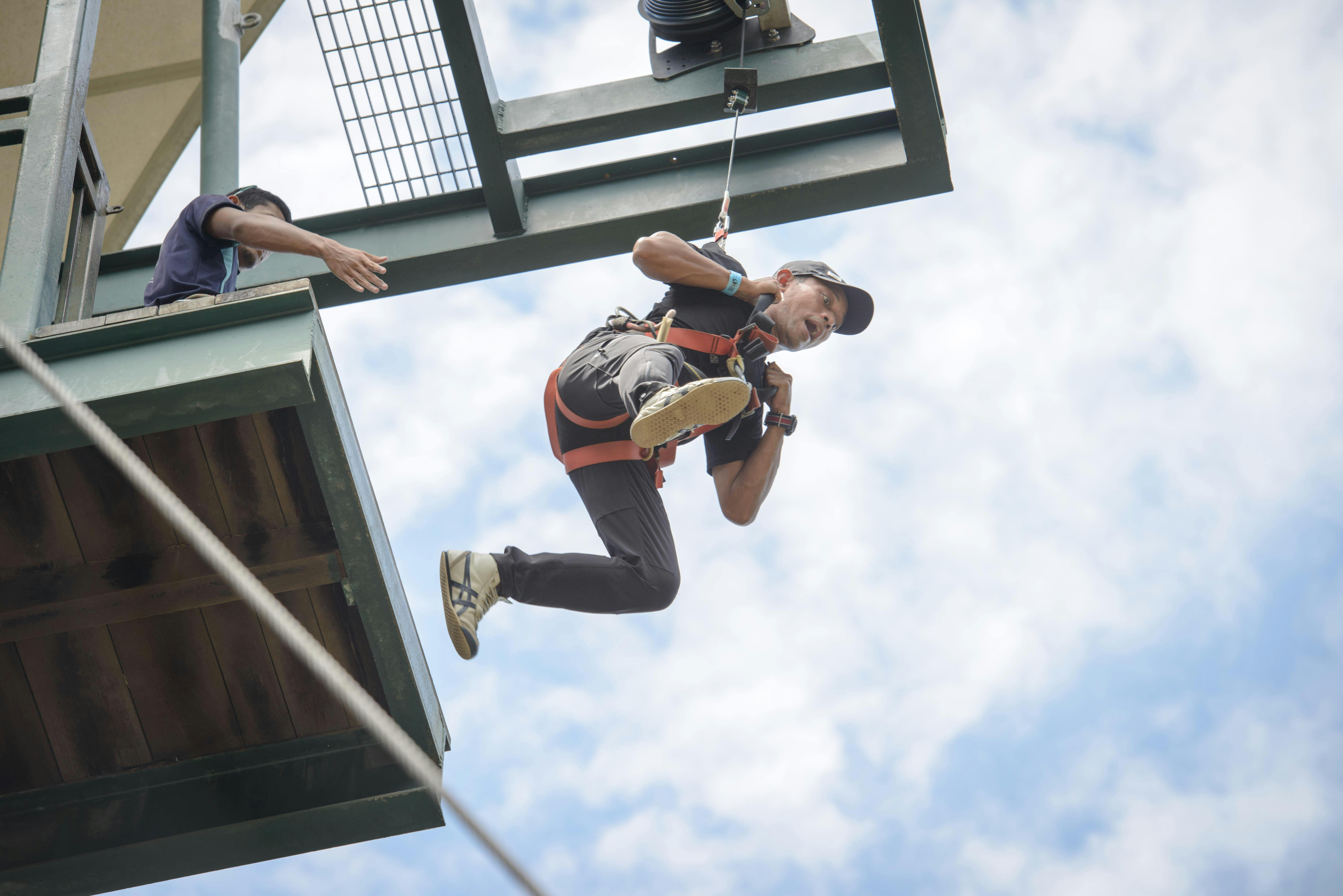 맑고 푸른 하늘을 배경으로 플랫폼에서 하네스와 헬멧을 착용한 사람.