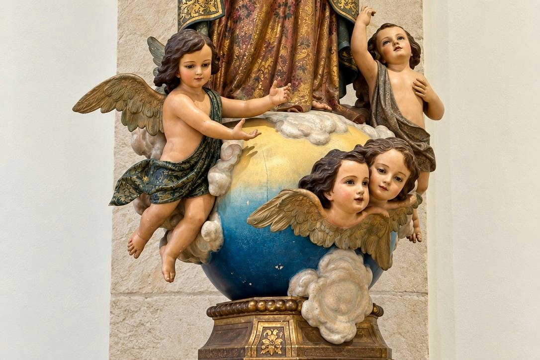 A sculpture featuring cherubs with wings surrounding a globe, adorned with clouds, on a decorative pedestal.