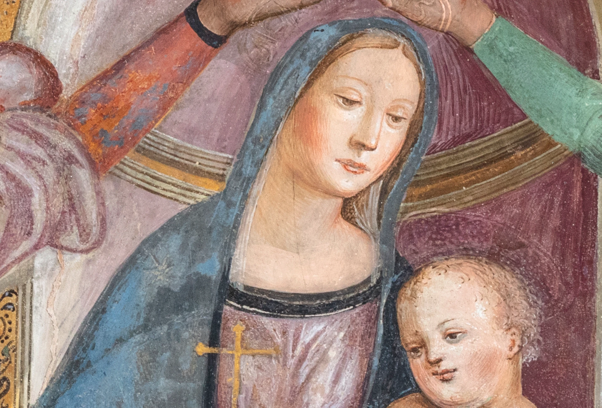 A woman sitting with a child on her lap is crowned by two angels under a decorative ceiling.