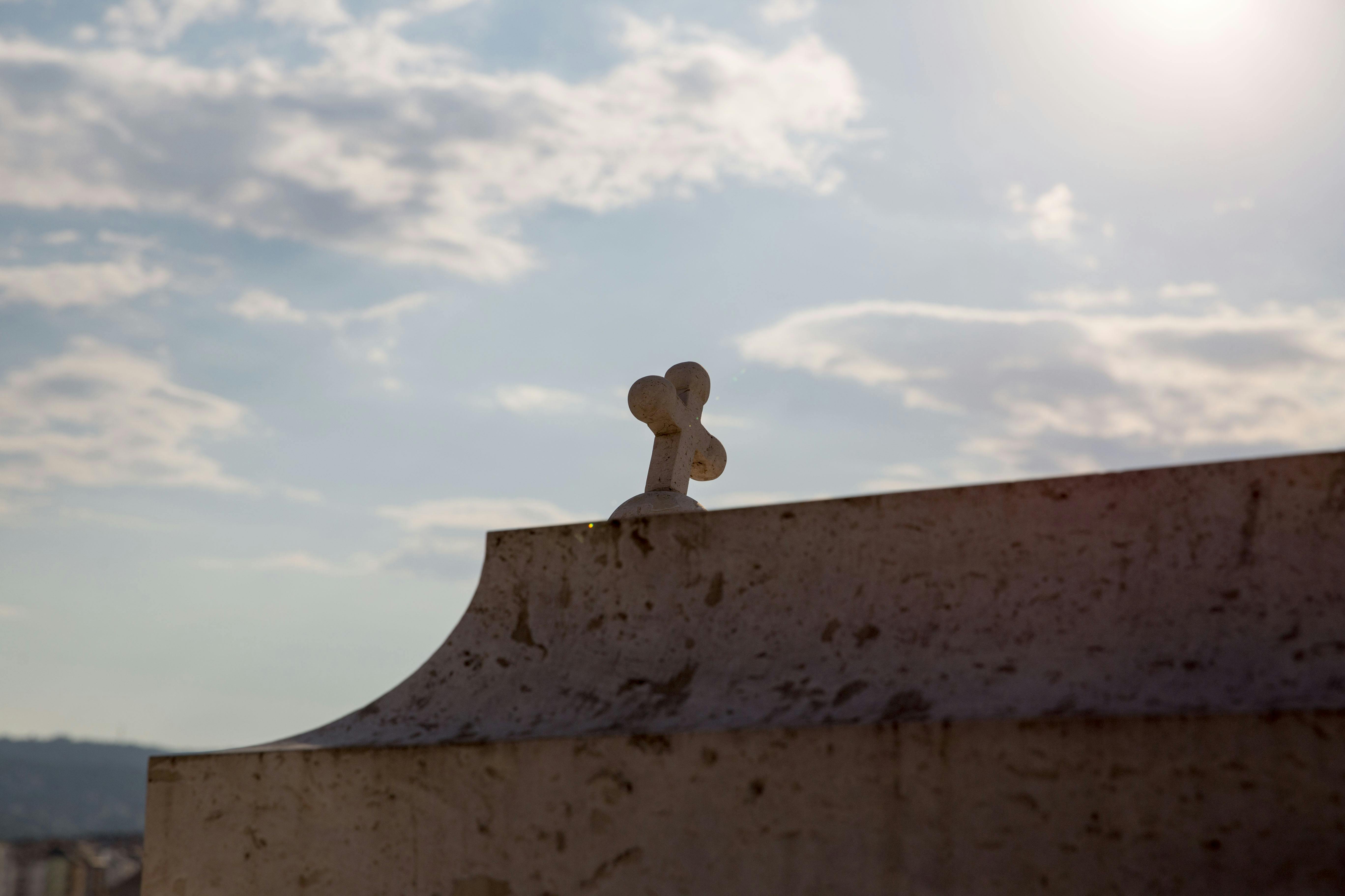 曇り空と明るい日差しに照らされた風化した建物の上に石が交差しています。