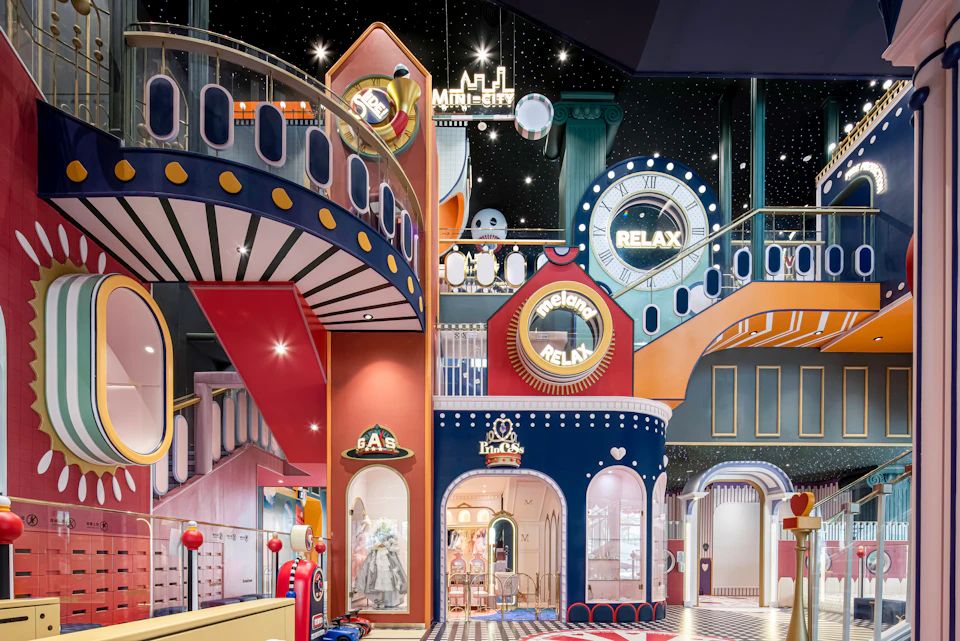 A whimsical indoor play area with colorful structures, signs like "Relax," and a starry sky ceiling, resembling a themed cityscape.