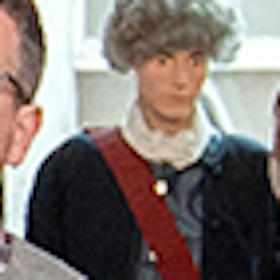 Two people in a museum exhibit featuring a statue and informational displays, viewed through a stone archway with wooden doors.