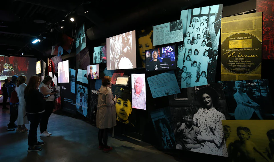 Person viewing various photos and videos on a multimedia wall display, featuring historical images and documents.