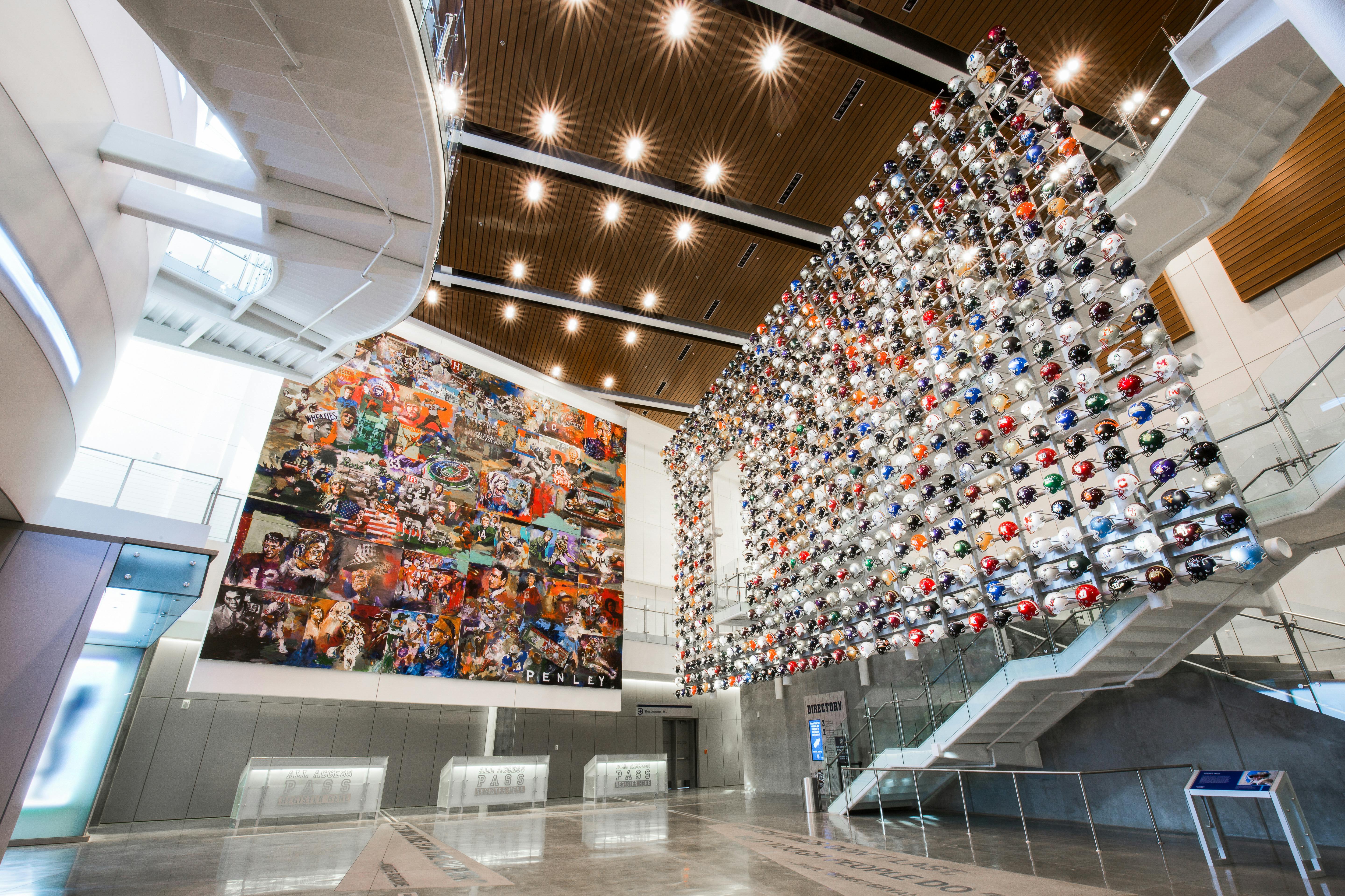 Prostorný interiér s velkou stěnou z fotbalových přileb, barevnou nástěnnou malbou a proskleným schodištěm vedoucím do druhého patra.