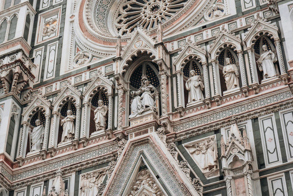 Detailed exterior of a Gothic cathedral featuring intricate carvings, statues of saints, and a large rose window.