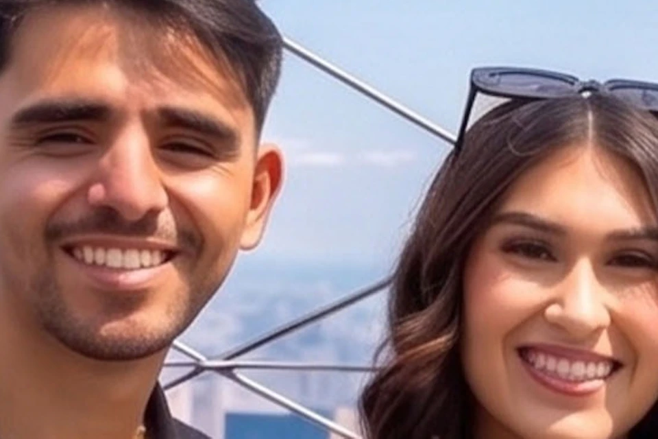 Two people smiling and posing with a mascot dressed as a skyscraper on a rooftop observation deck under a blue sky.