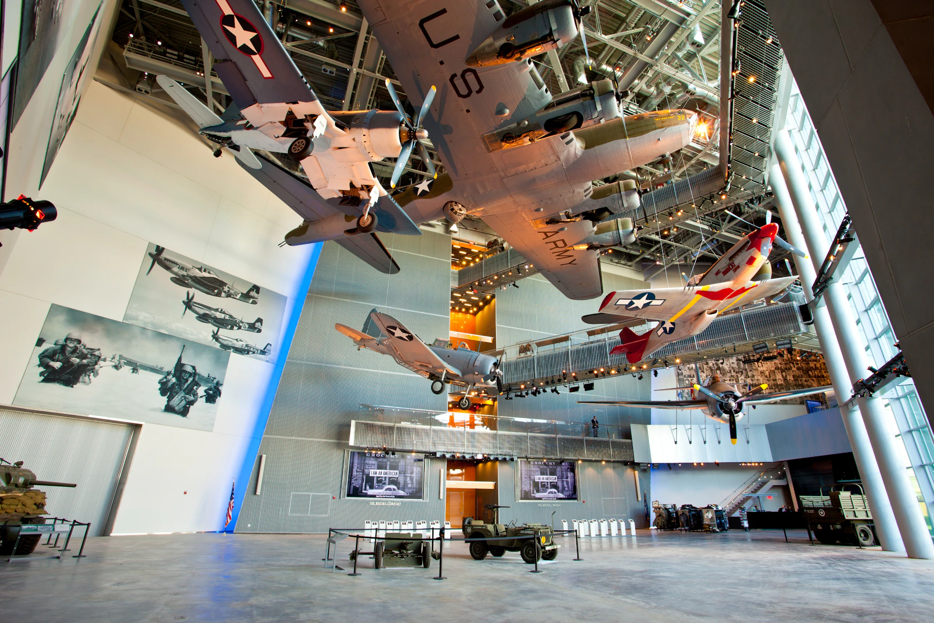An indoor aviation museum with vintage military planes suspended in the air and historical displays on the walls.