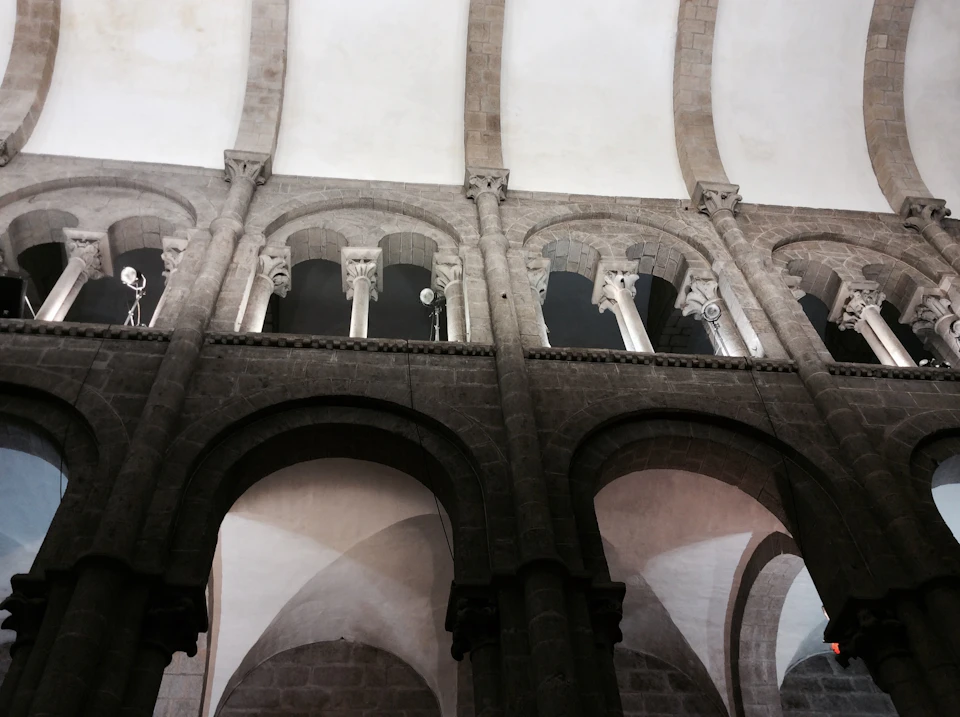 Stone arches and columns inside a historic building with ornate capitals and high ceilings.
