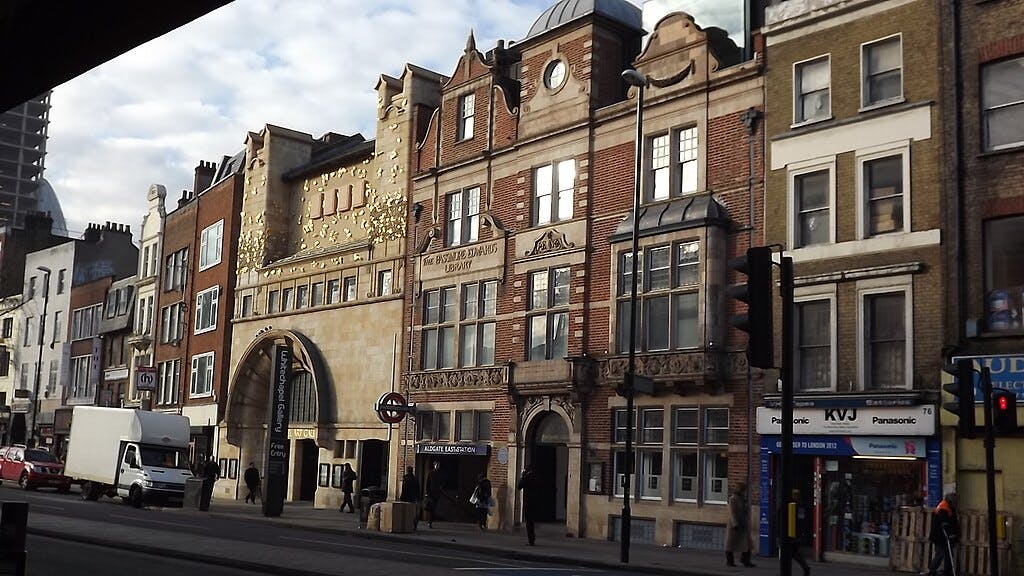 ビショップスゲート・インスティテュートや様々なショップを含むアルドゲートの歴史的建造物のストリートビューで、歩行者や車両が通り過ぎています。