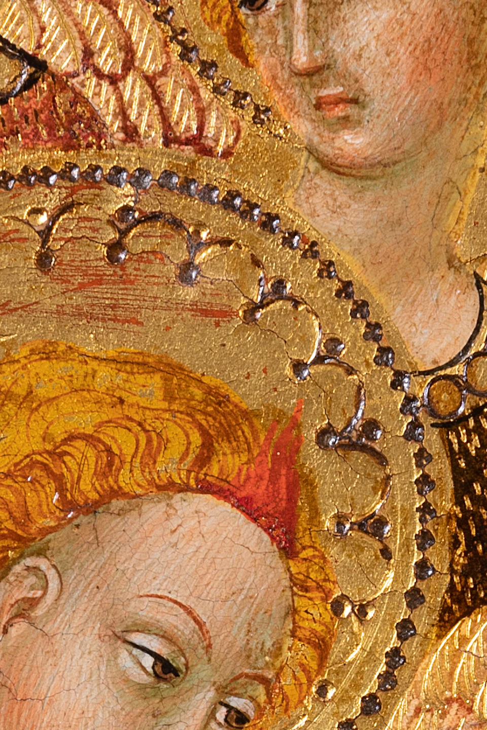 Medieval painting of two angels with halos, one in red playing a stringed instrument, on a gold ornate background.