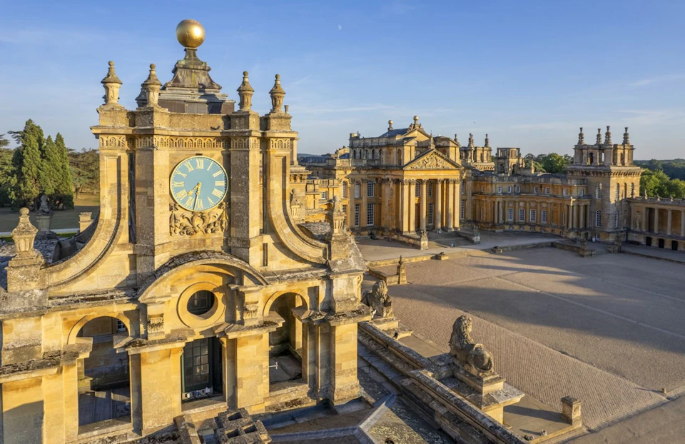Historic palace with ornate architecture, featuring a clock tower and colonnaded buildings, under a clear blue sky.