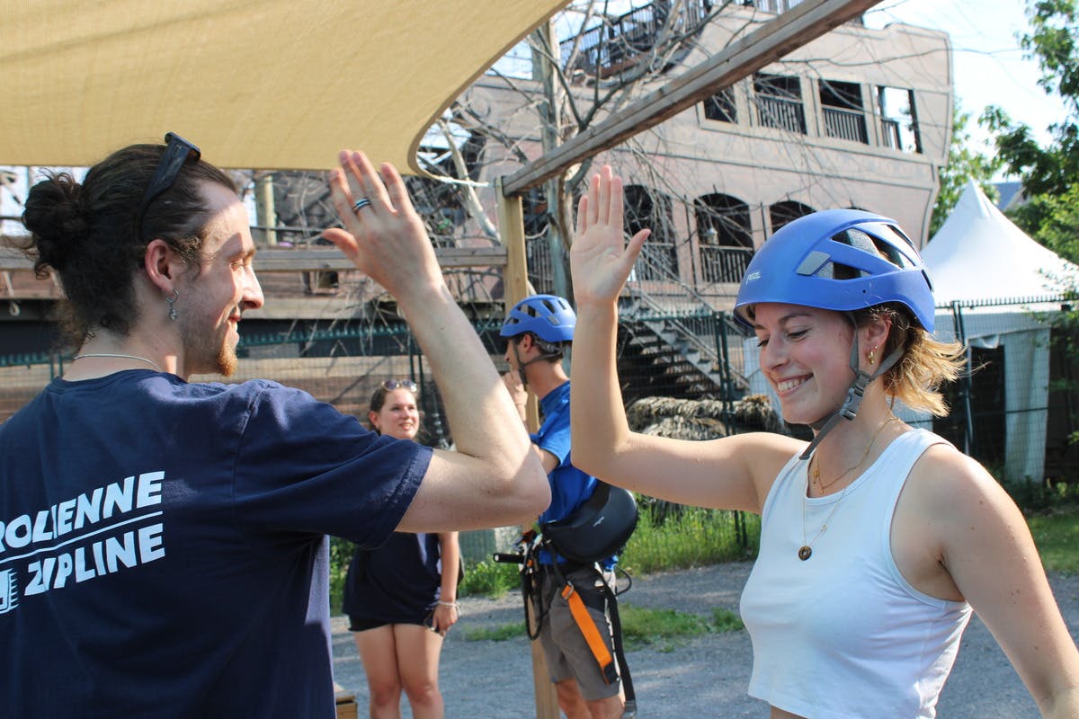 Persona con casco che sorride e dà il cinque. Le persone sullo sfondo sono equipaggiate in modo simile. Ambientazione esterna.