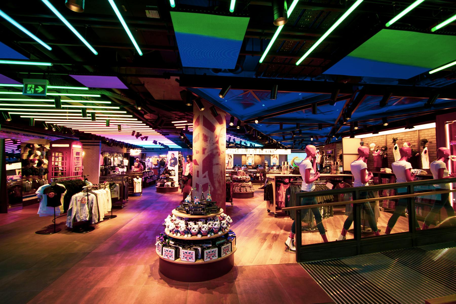 Tętniące życiem wnętrze sklepu detalicznego z kolorowym oświetleniem, ekspozycjami ubrań, manekinami i półkami na pamiątki.