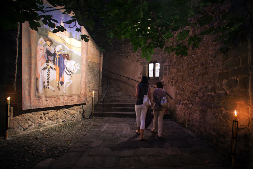 Two women walking up a stone staircase next to a wall mural depicting horses and people in historical clothing.