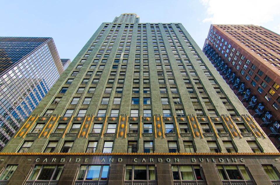 Tall, green art deco skyscraper with gold accents, seen from below. The lower facade shows the name “Carbide and Carbon Building.”