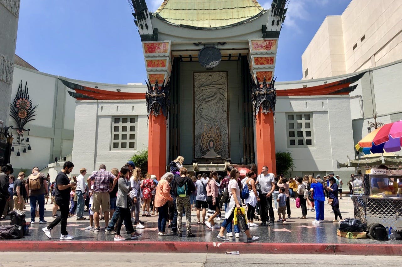 赤い柱と細かい装飾が施された大きな華やかな建物の入口の外には、大勢の人々が集まっていました。