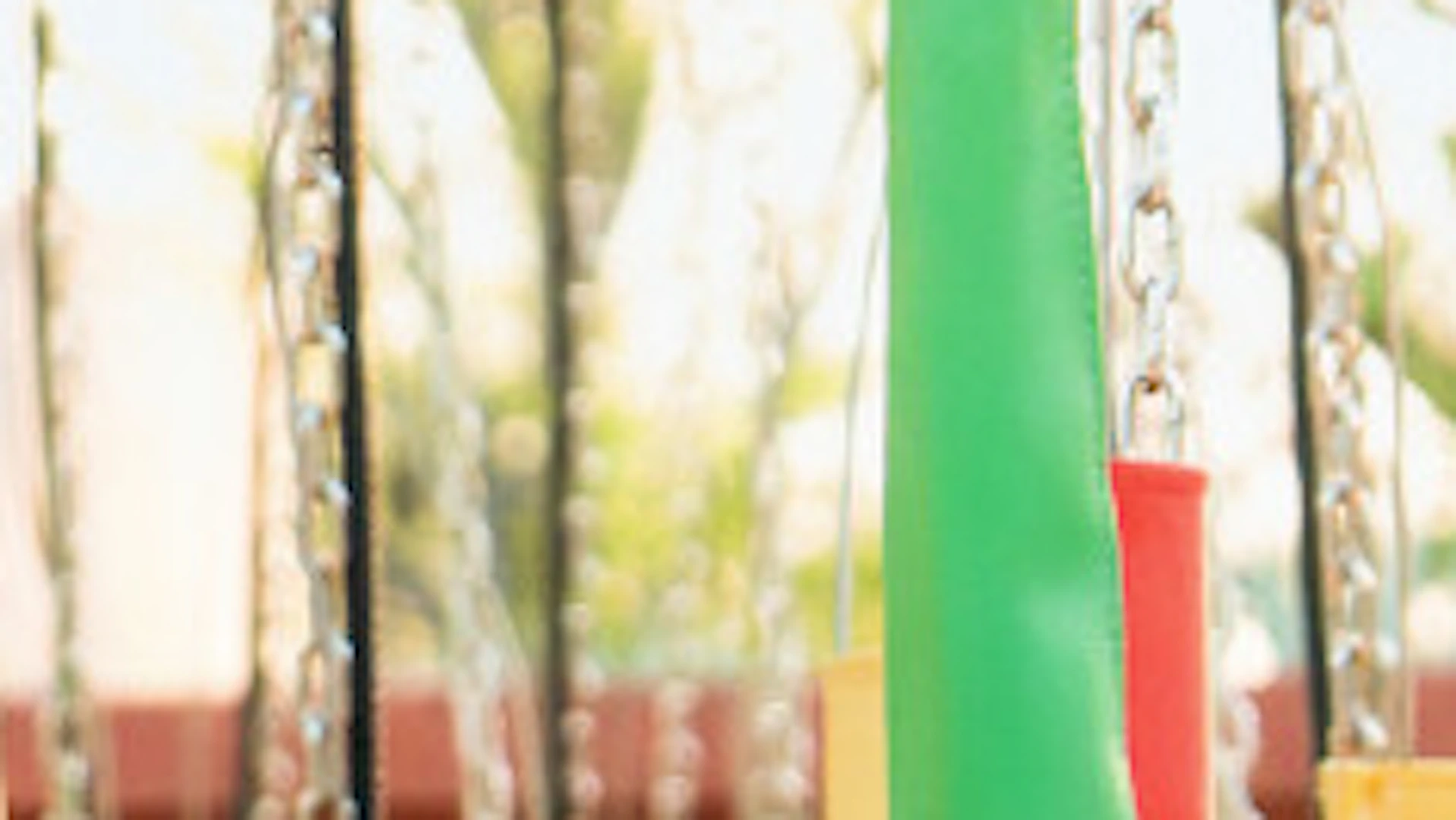A person joyfully riding a colorful swing carousel at an amusement park, with vibrant designs and sunny weather.