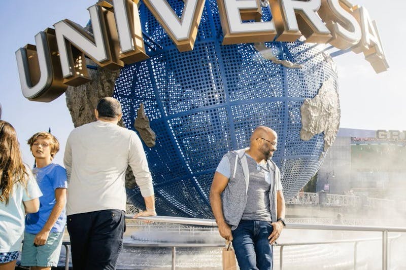 Een groep mensen staat voor een grote blauwe wereldbol met "UNIVERSAL" erop geschreven.