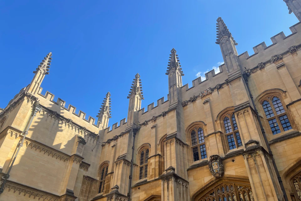 A historic stone building with pointed spires and arched windows against a clear blue sky.