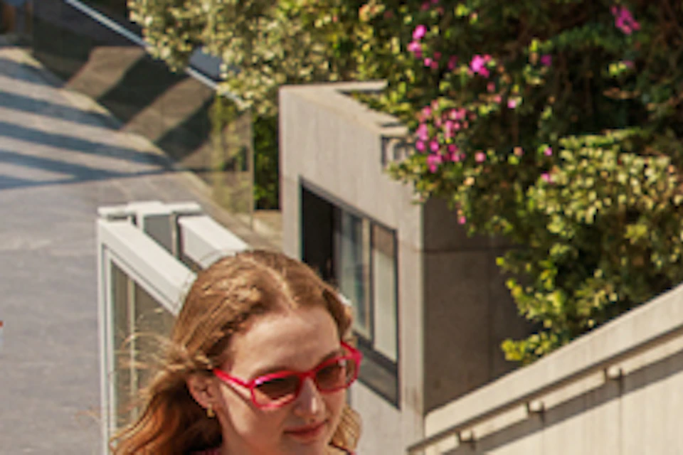 A group of people standing outside the Acropolis Museum entrance, near a stairway and blooming bougainvillea flowers.
