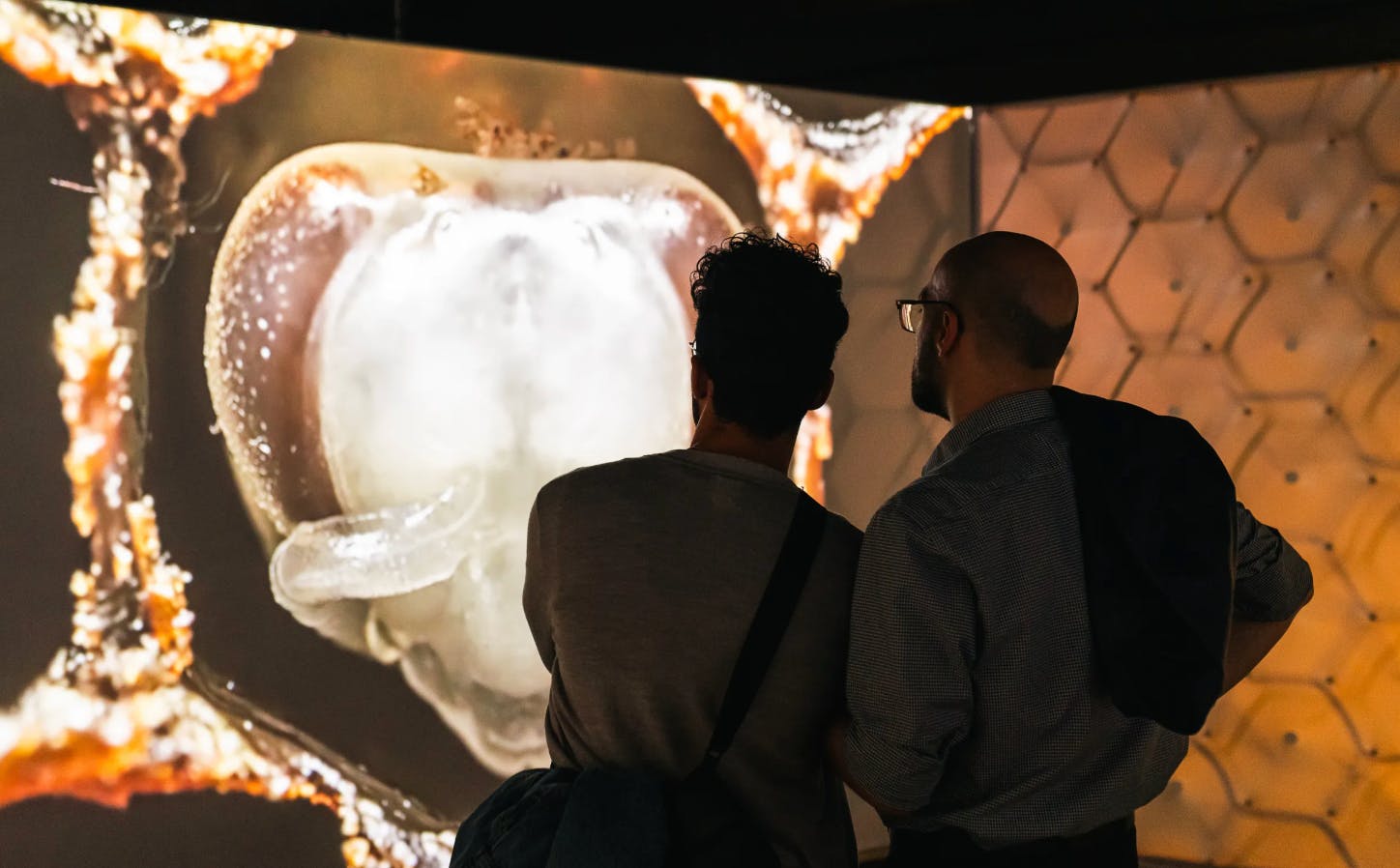Twee mensen staan voor een groot verlicht scherm waarop een uitvergrote close-up van een biologische structuur te zien is.