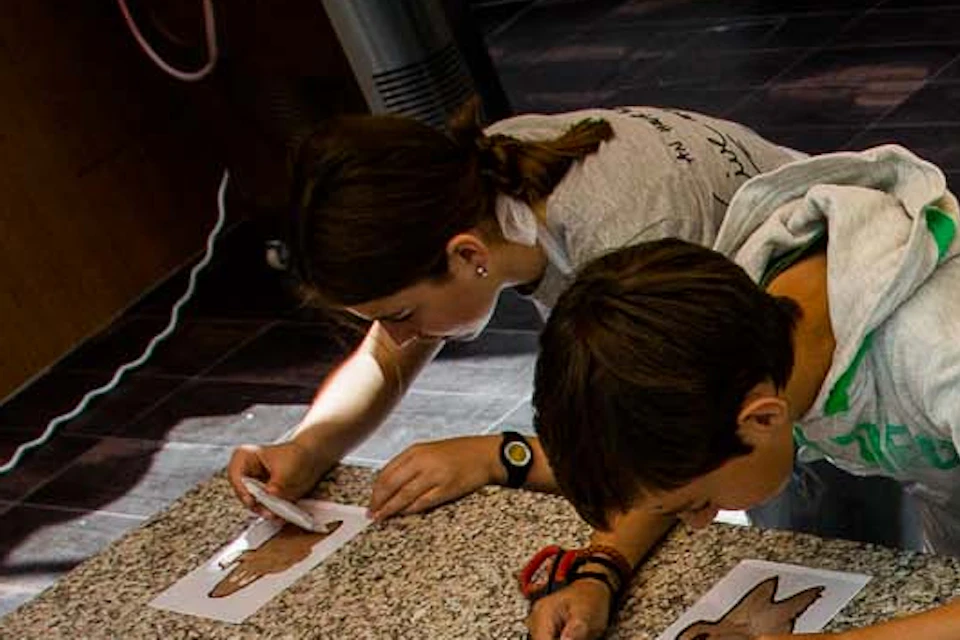Group of children decorating gingerbread men with icing at a kitchen counter, all focused on their individual cookies.