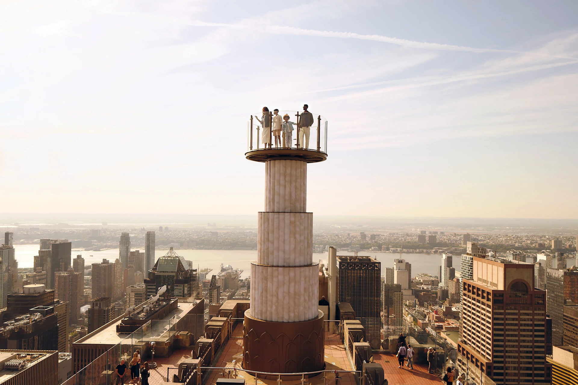 People standing on an elevated viewing platform atop a tall building, overlooking a cityscape with numerous skyscrapers and a river.