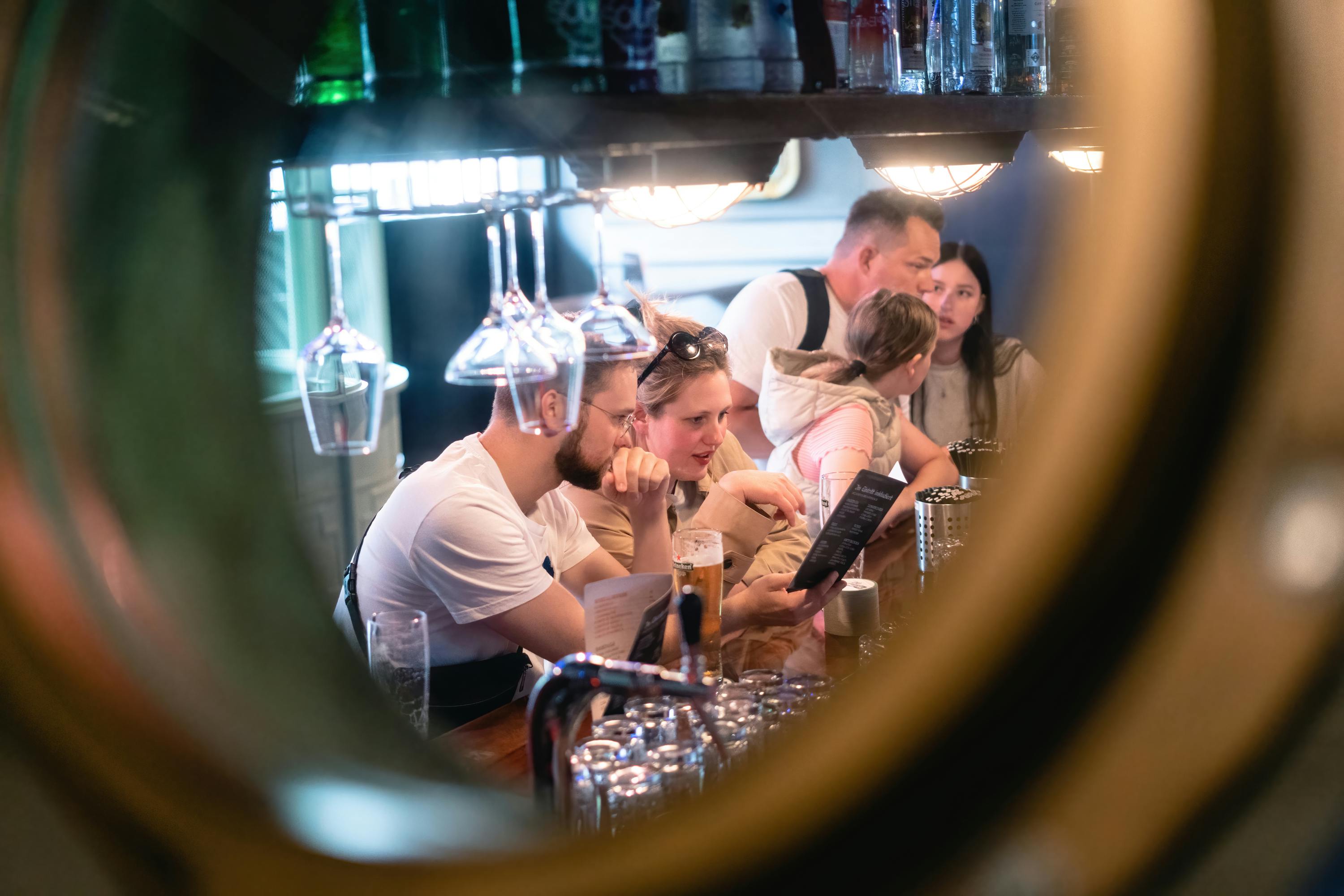 원형 프레임에 걸린 유리 제품과 선반이 보이는 바에 앉아 독서 메뉴를 즐겨보세요.