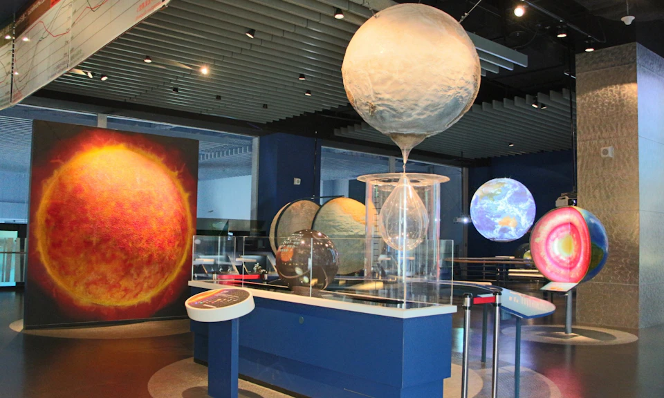 A science exhibit featuring planet models, including the Earth and the Sun, and a demonstration involving a water globe.