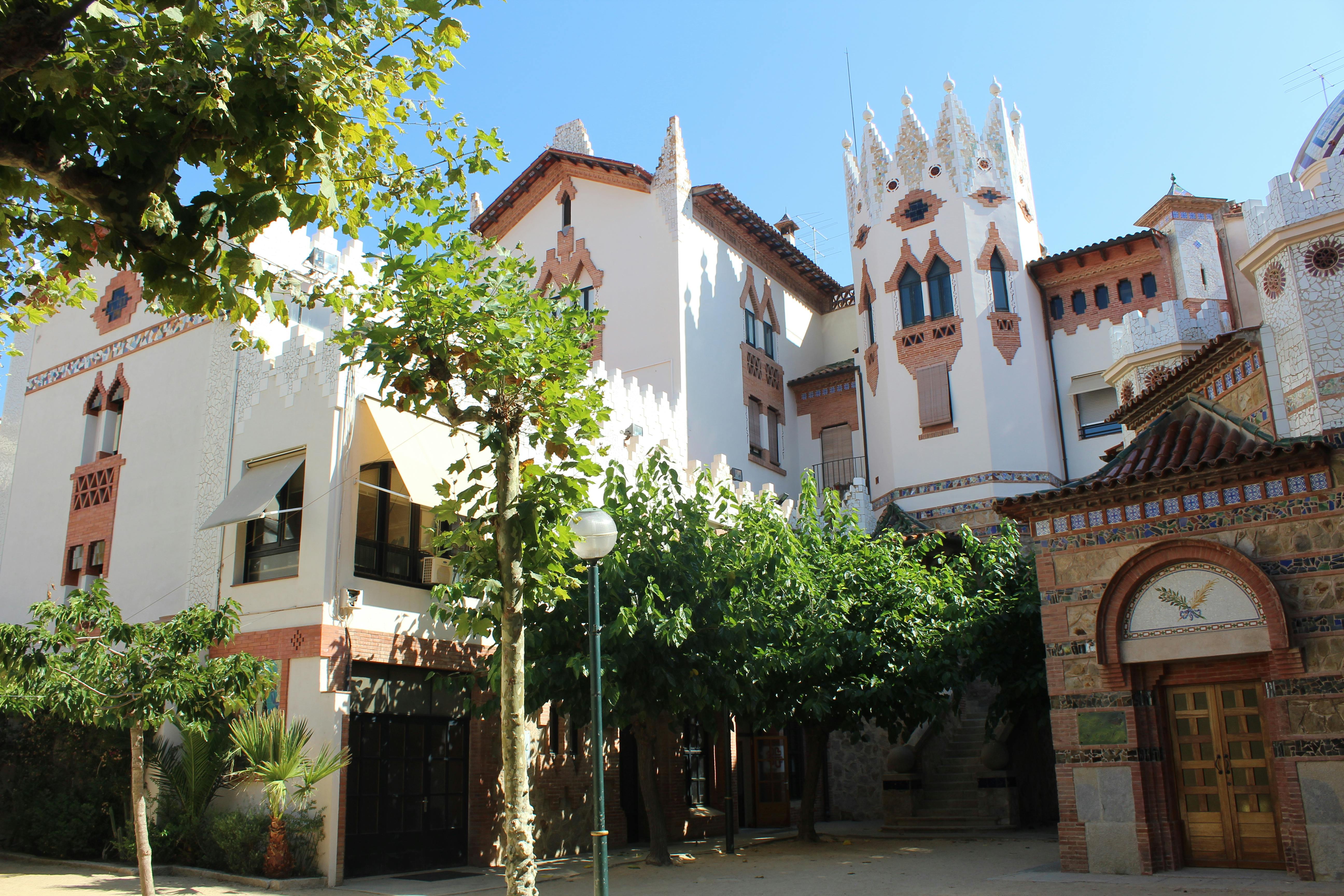 一栋白色华丽建筑，装饰以砖为主，四周环绕着郁郁葱葱的树木，阳光明媚。