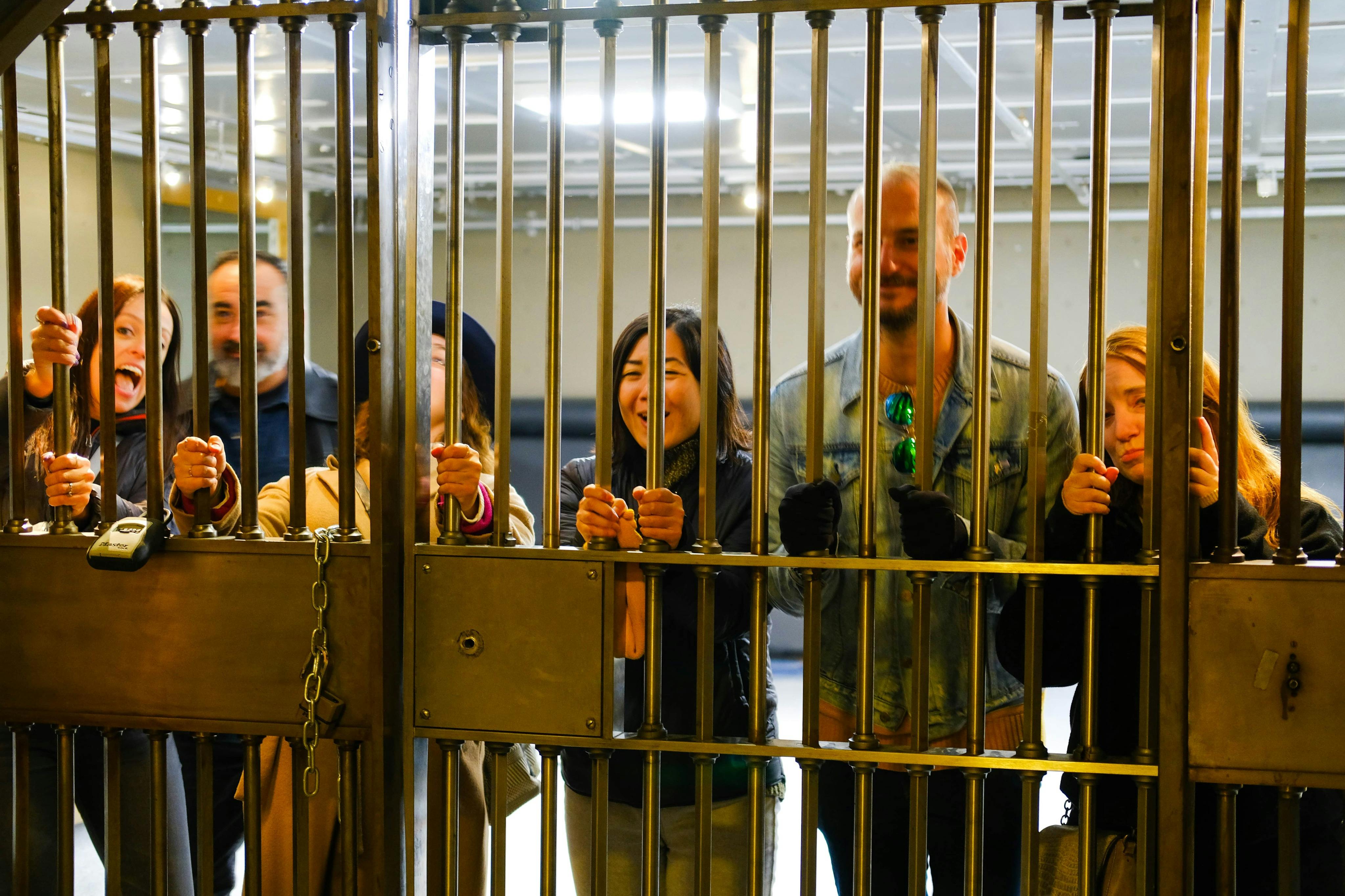 一群人站在金属大门后面，微笑着拿着栅栏。 背景显示室内环境。