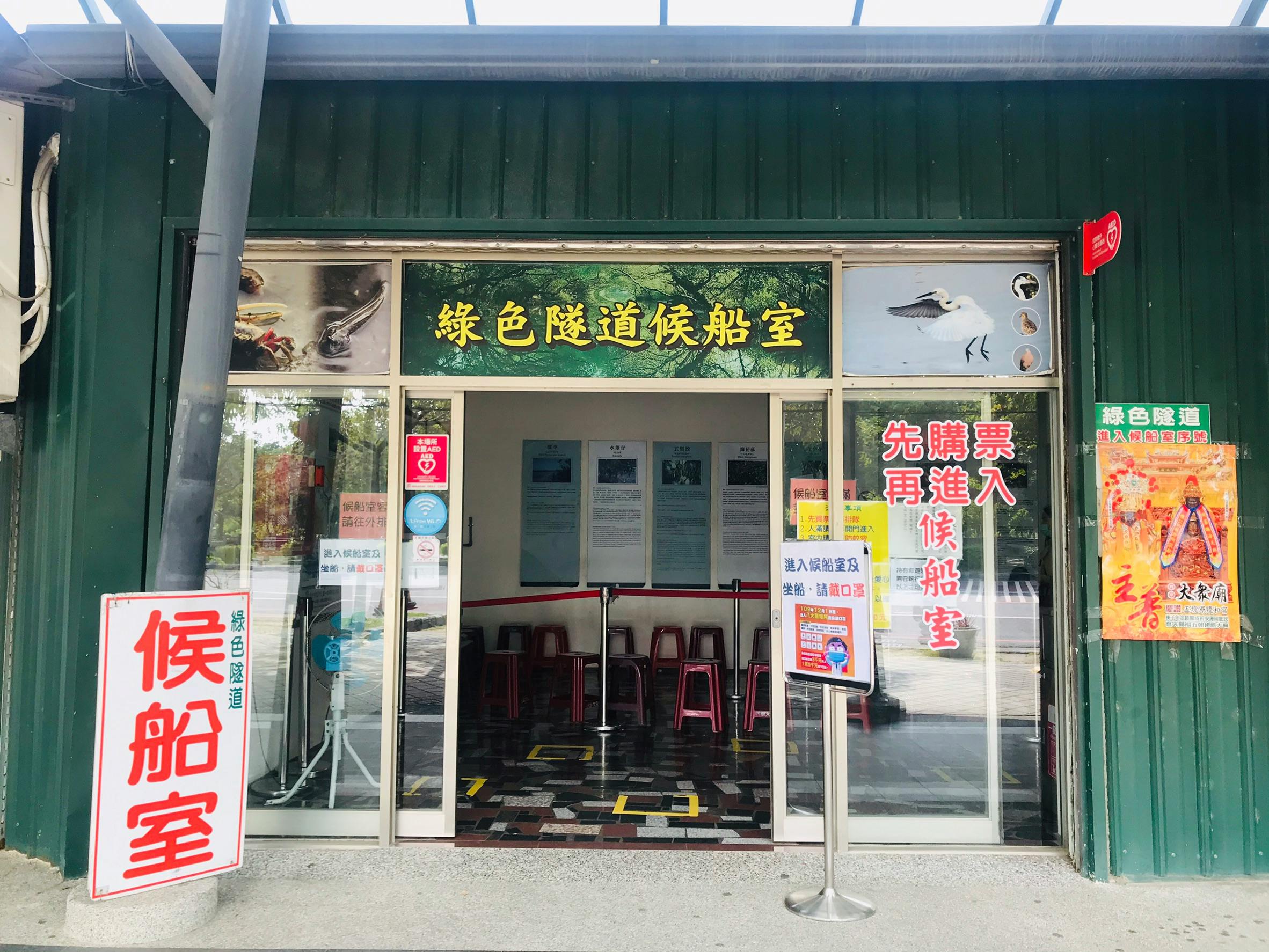 Entrance to a building with glass doors, signage featuring birds, and chairs inside. Text in Chinese is displayed on signs.
