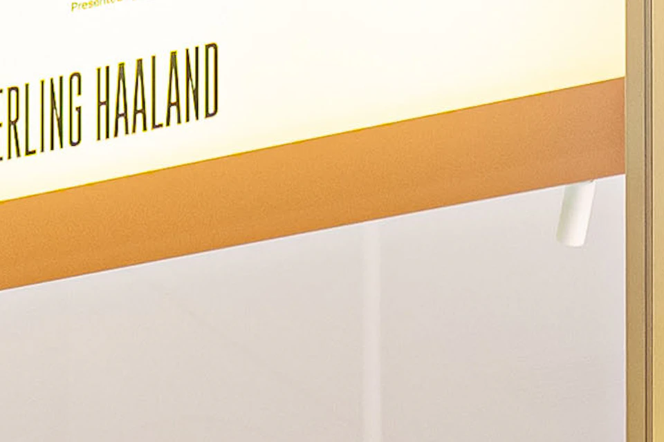 A display case with life-size posters of soccer players, team jerseys, and logos of football leagues and tournaments.