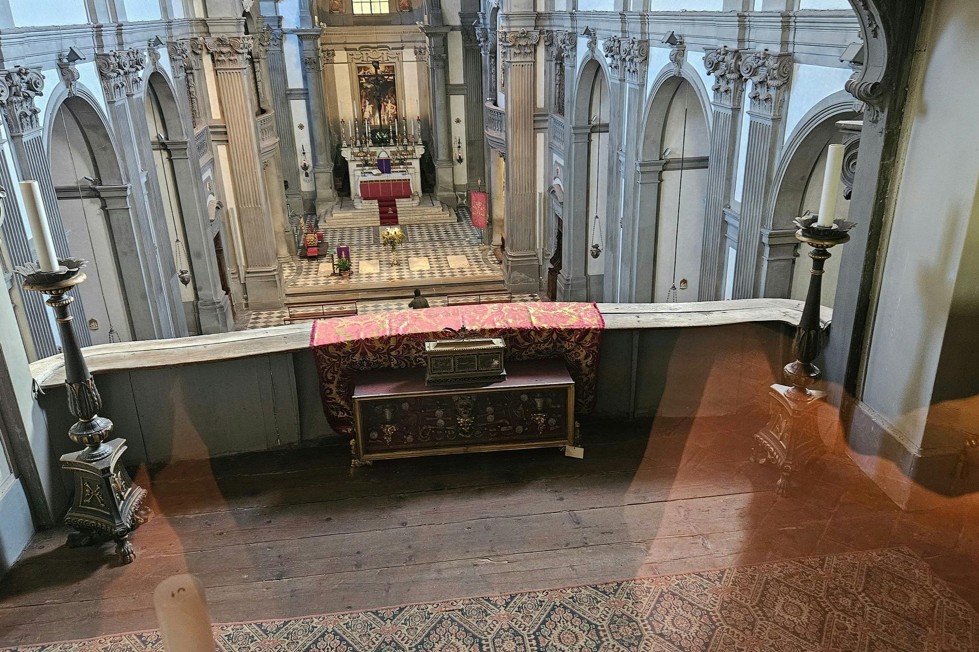 赤い布の祭壇、装飾的な要素、建築のディテールを備えたバルコニーから、華やかな教会の内部を眺めることができます。