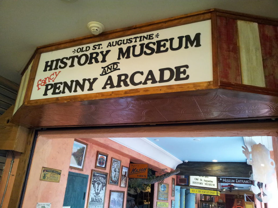 Entrance to the "Old St. Augustine History Museum and Fancy Penny Arcade" with vintage posters and decor visible inside.