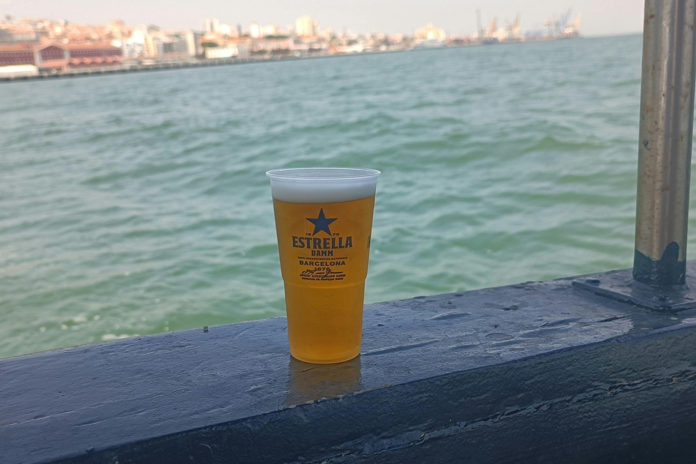 棚の上にはEstrella Dammビールが1杯置かれており、水域と街並みが背景になっています。