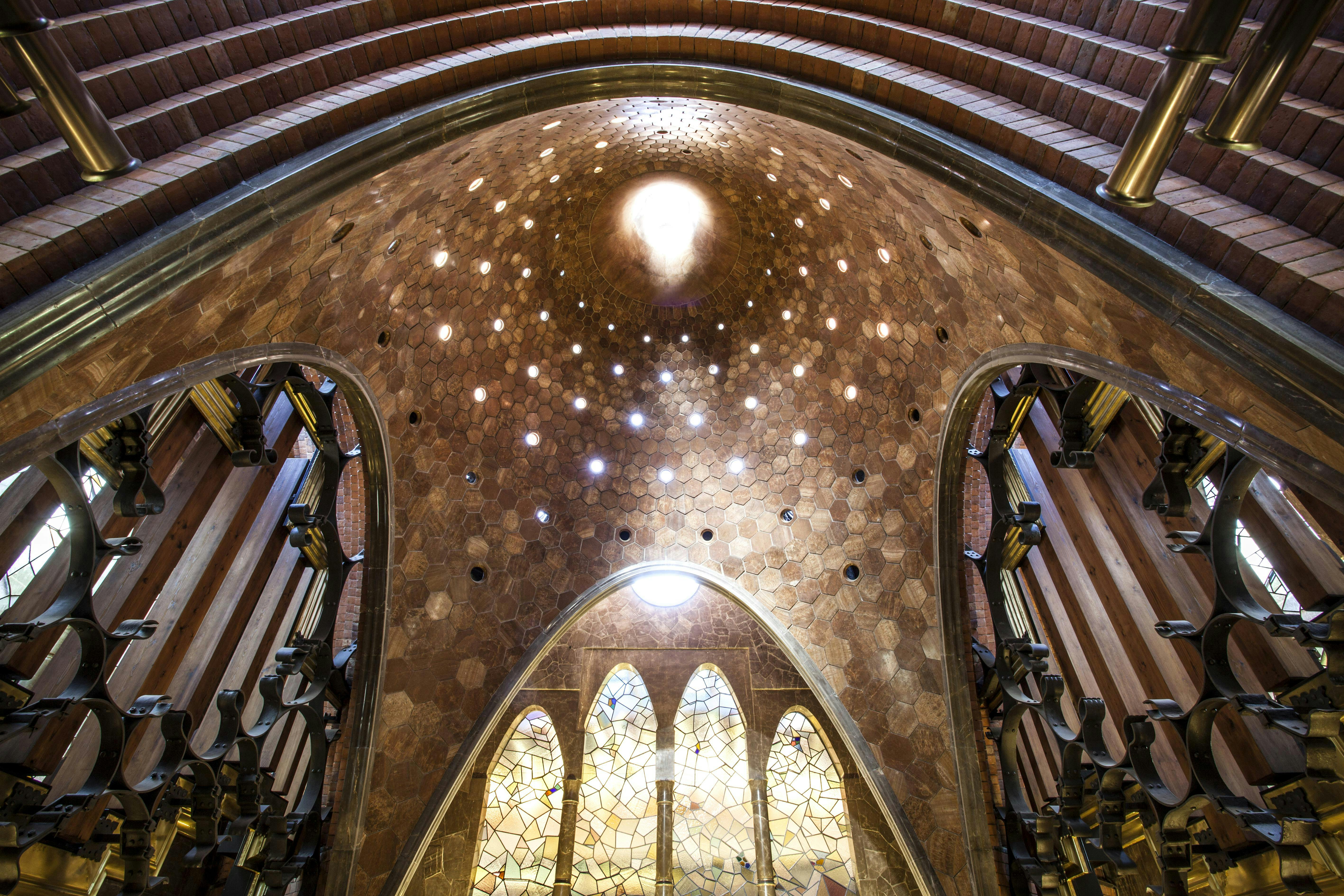 Interior view of a church dome with hexagonal patterns, stained glass windows, and organ pipes on both sides.