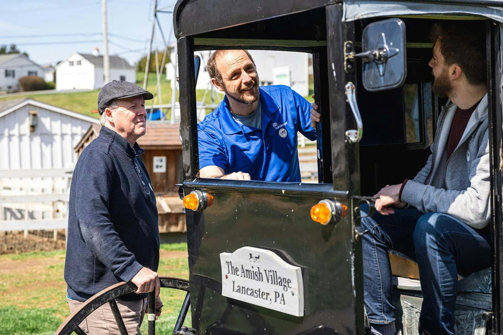 Two men, one inside an Amish buggy and the other standing outside, at The Amish Village in Lancaster, PA.