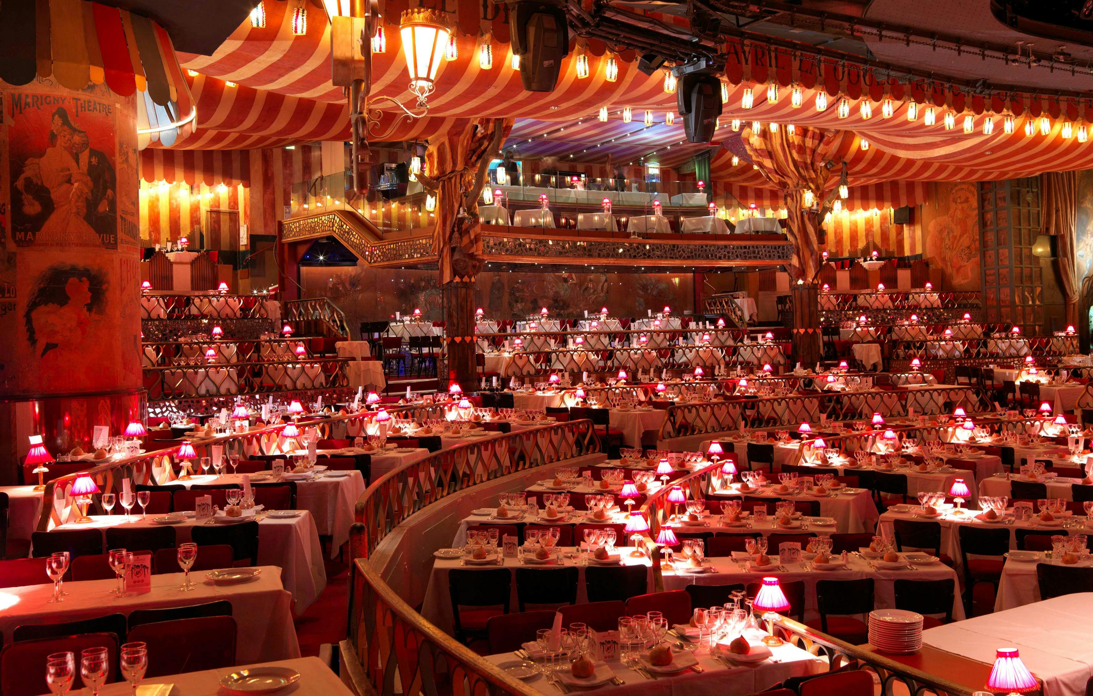 Lavishly decorated banquet hall with white tablecloths, red lighting, and striped drapery creating an elegant atmosphere.