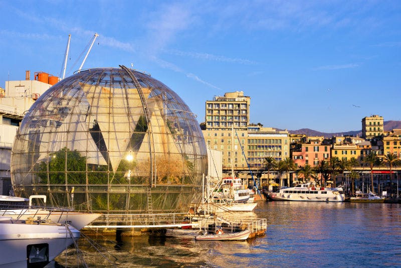 靠近海滨的玻璃球结构，后面有船只、建筑物和晴朗的蓝天。