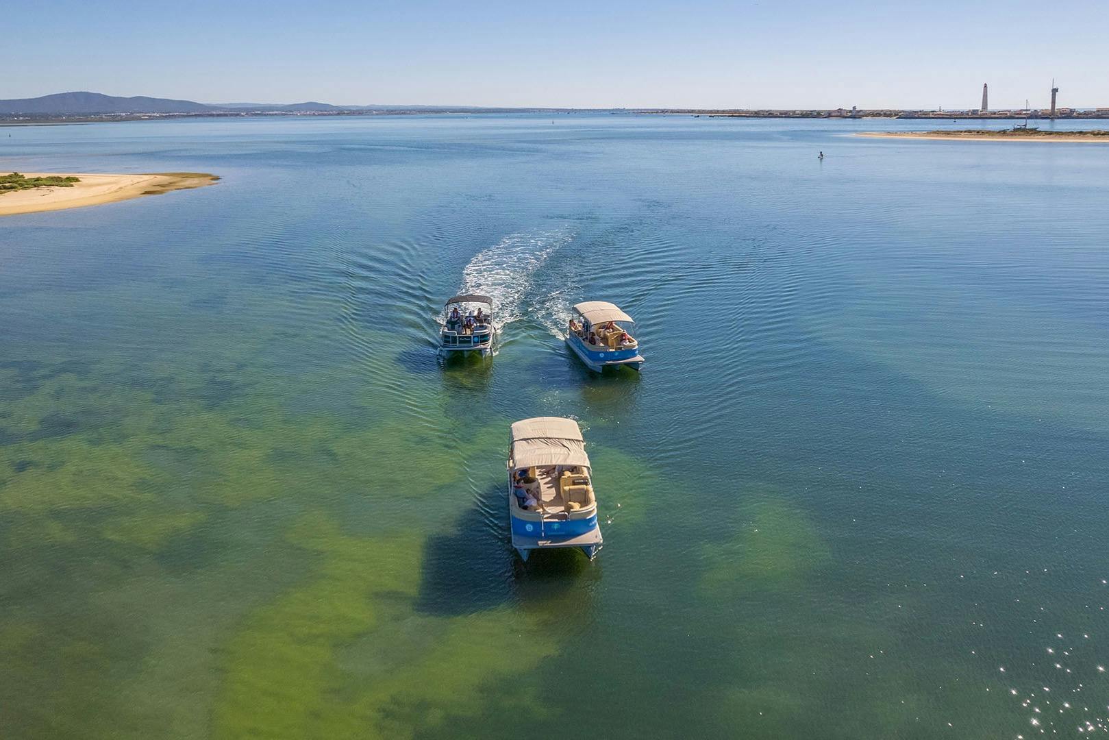 Лодки Formosamar курсируют по чистым, мелководным зеленым водам с отдаленной береговой линией и маяками под солнечным небом.