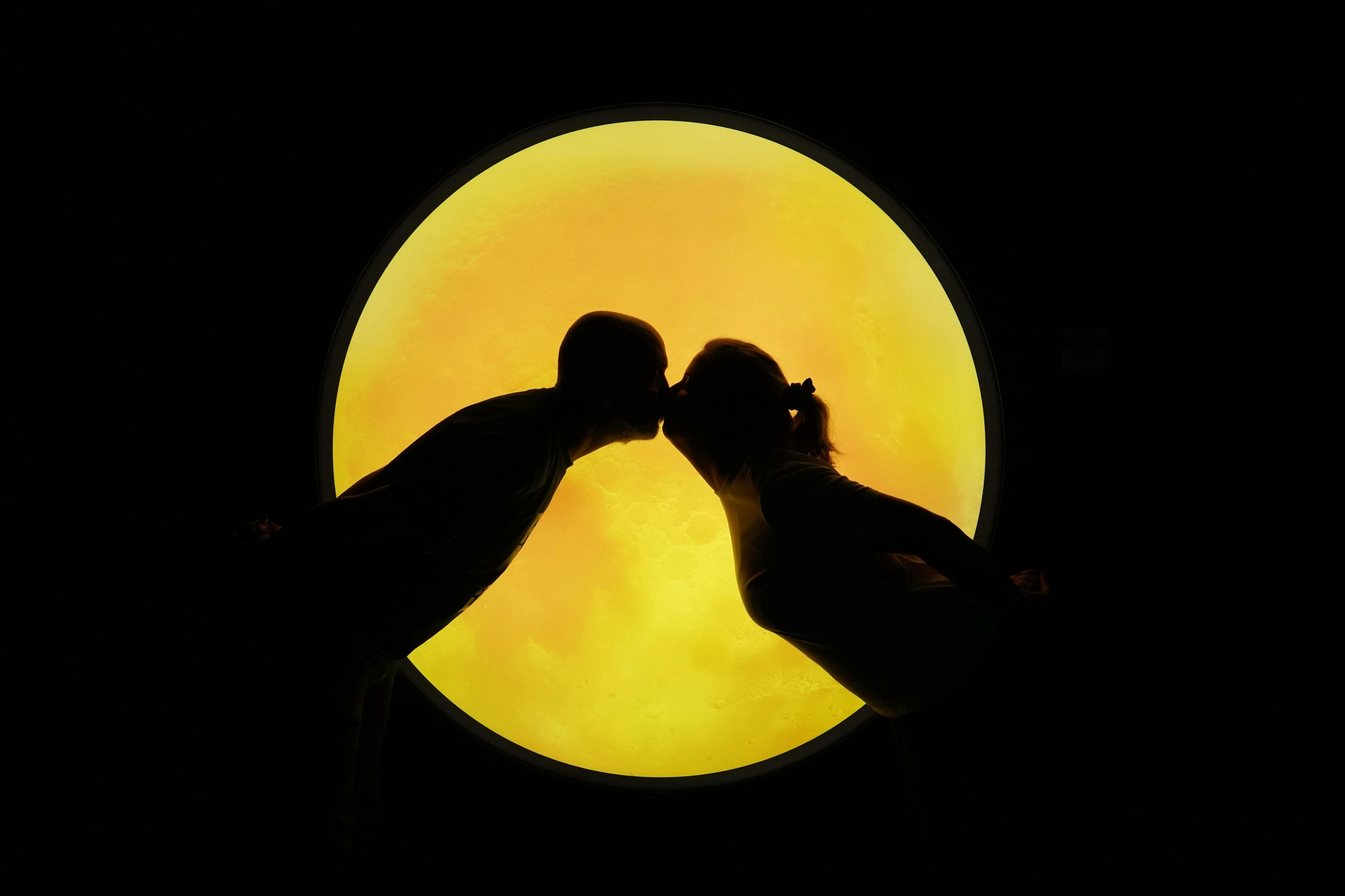 两个人围绕着闪闪发光的黄色圆形背景，仿佛在亲吻。