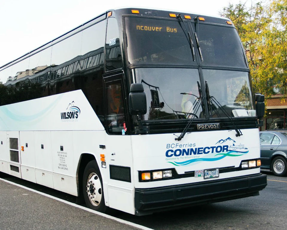 A white tour bus with "BC Ferries Connector" logo and "Vancouver Bus" displayed on the front, parked on a city street.