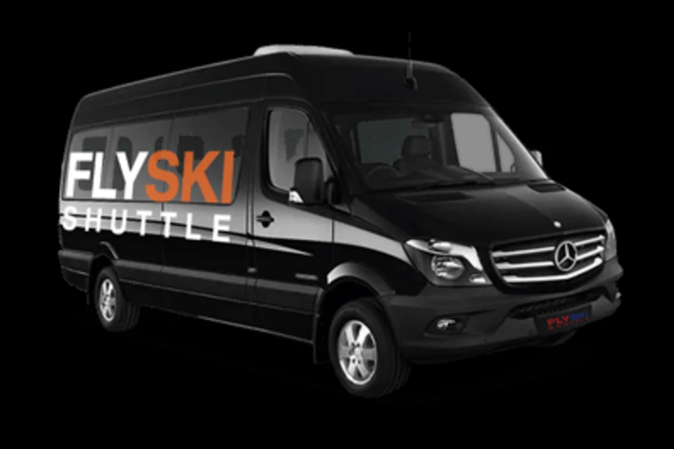 A black passenger van with the text 'SKI SHUTTLE' on the side in white and orange letters, against a black background.