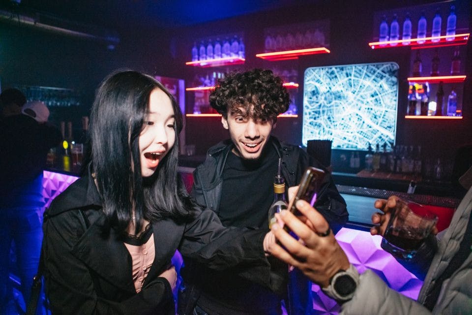 Dívka a kluk, kteří se překvapeně dívají na obrazovku telefonu