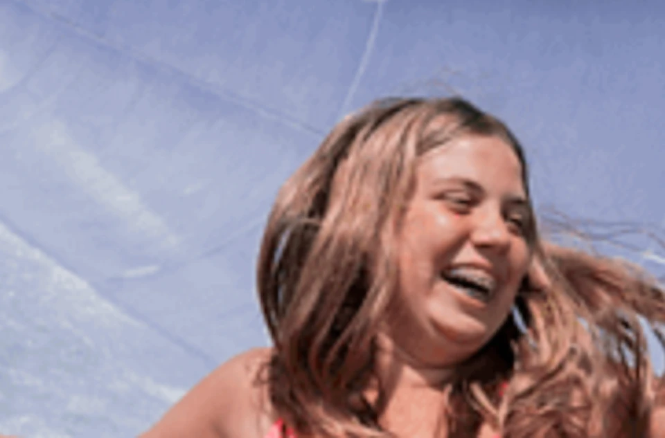 Three women in swimwear enjoying a water park ride on a yellow inflatable raft under a sunny sky.