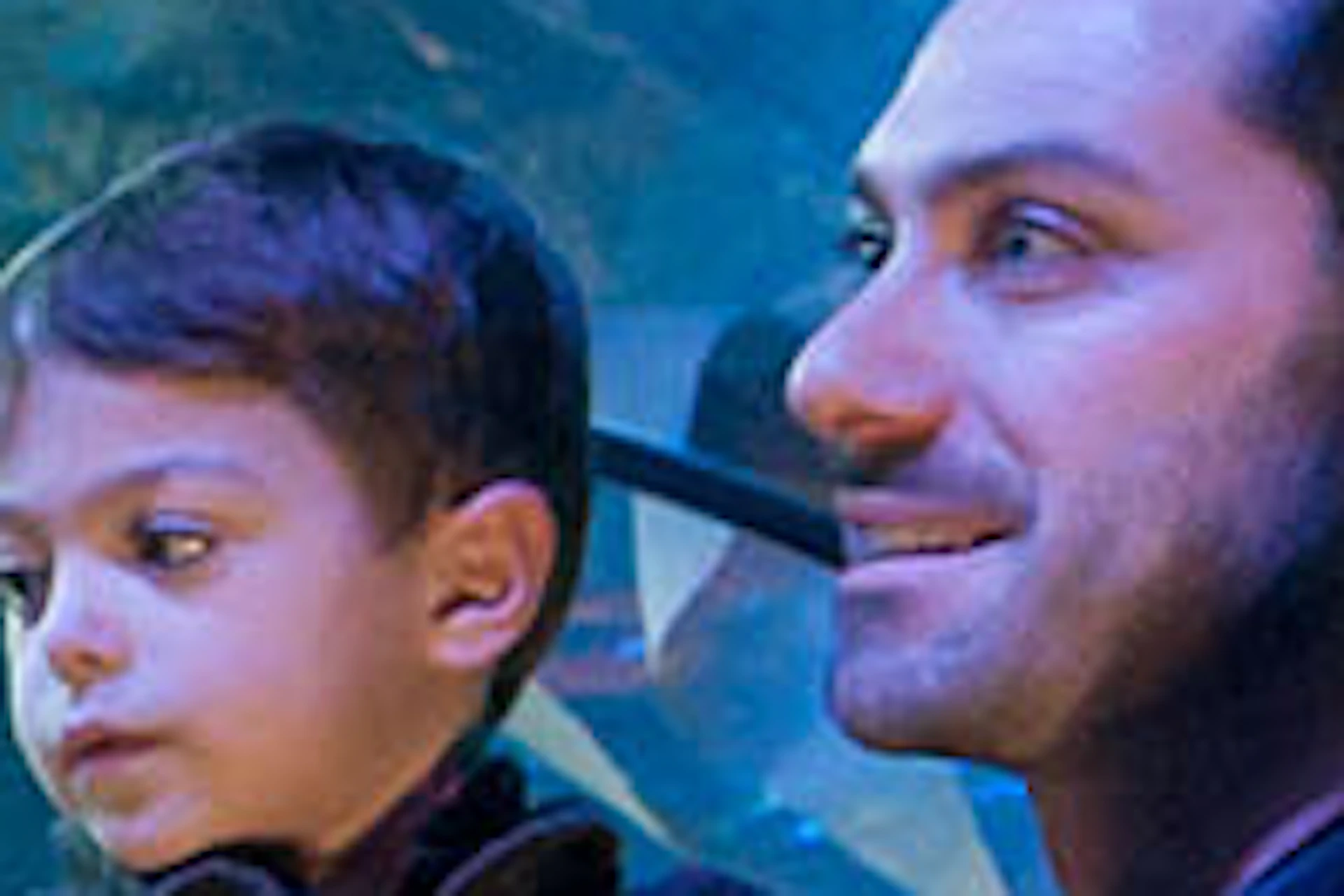 A family of four observes marine life through an underwater tunnel in an aquarium, surrounded by various fish and rays.
