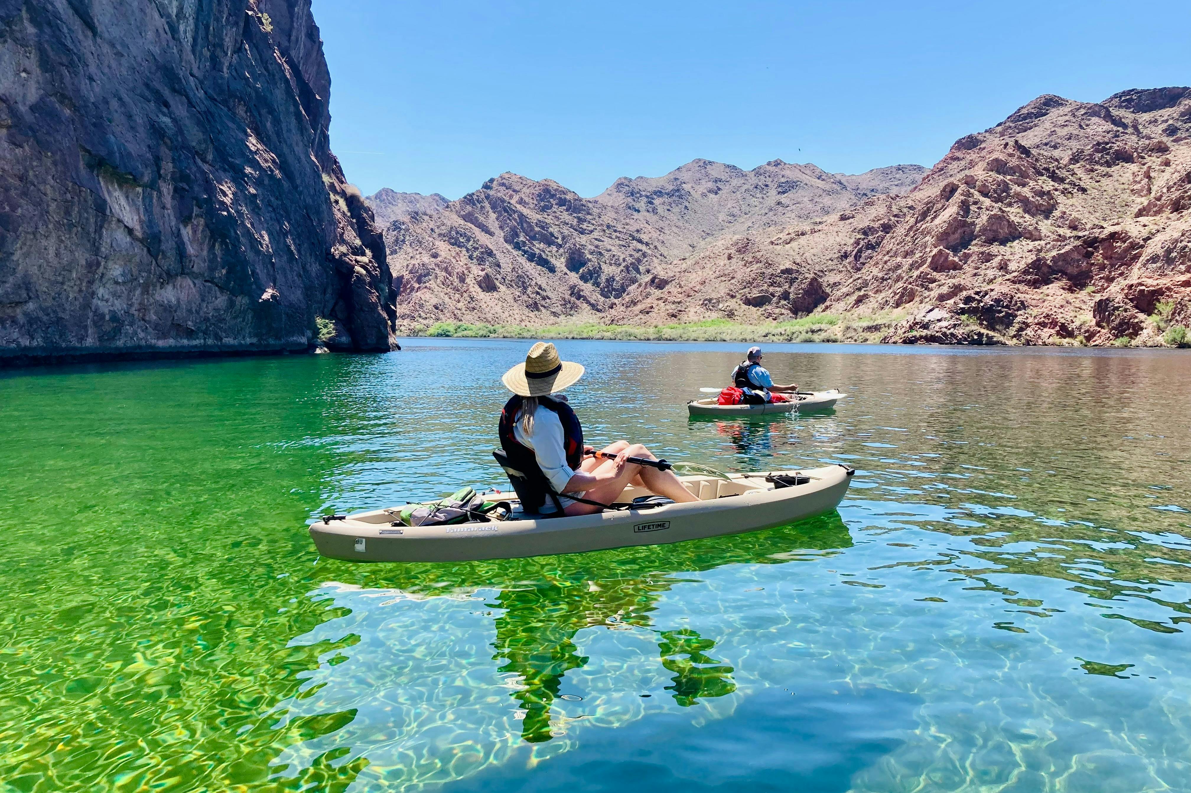 A kayaker relaxes and takes in the view of the mountains.