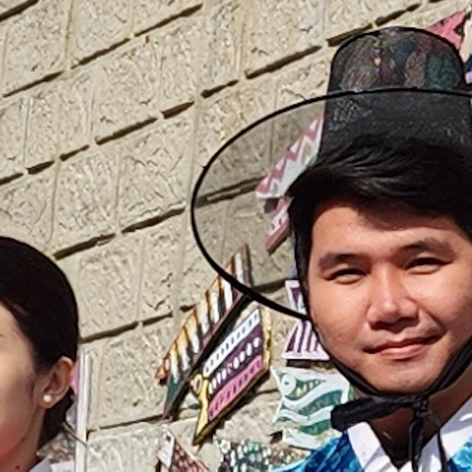 A group of people in traditional Korean attire posing in front of a decorative wall on a sunny day.